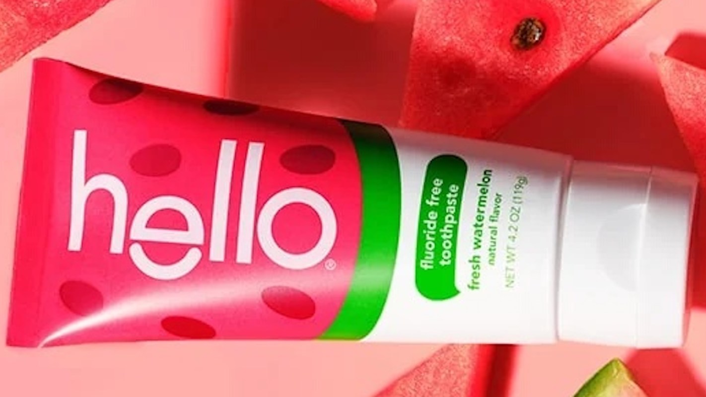A tube of watermelon-flavored toothpaste with a bright pink and white label surrounded by watermelon slices.