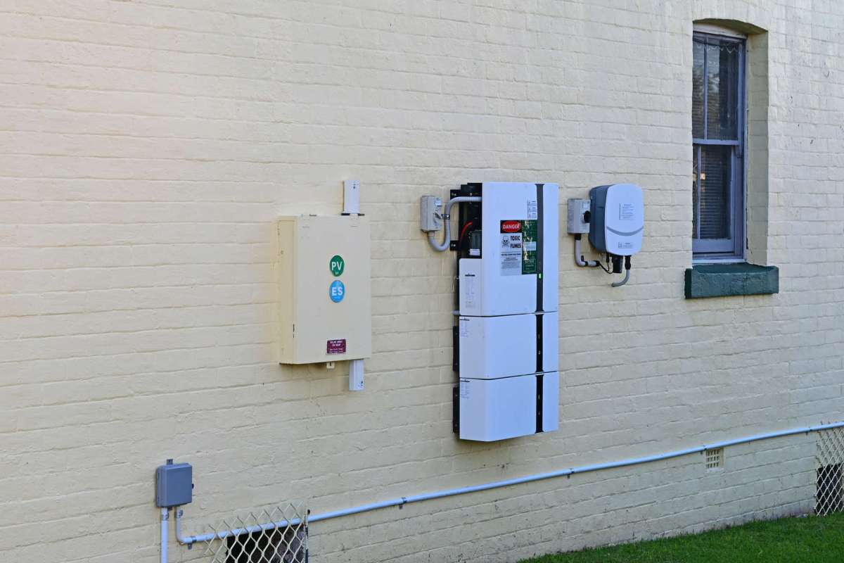 Electrical equipment mounted on a yellow brick wall next to a window.