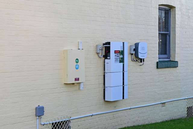 Electrical equipment mounted on a yellow brick wall next to a window.