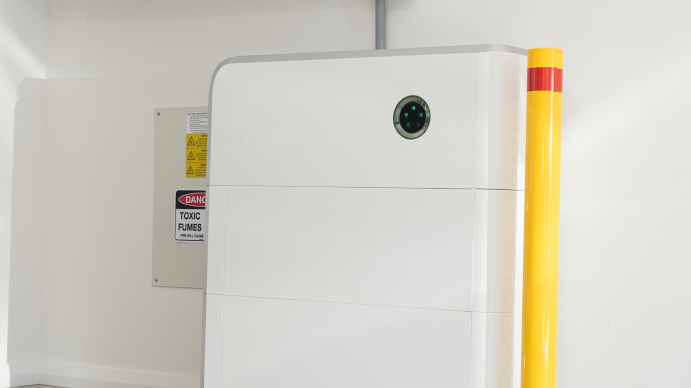 A white machine with a round sensor next to a warning sign about toxic fumes and a yellow safety post.