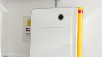 A white machine with a round sensor next to a warning sign about toxic fumes and a yellow safety post.