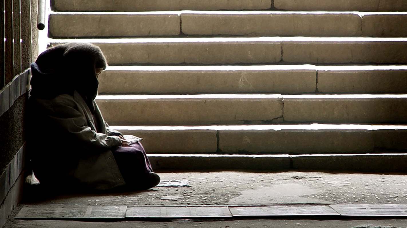 A person sitting on the ground at the bottom of a staircase.