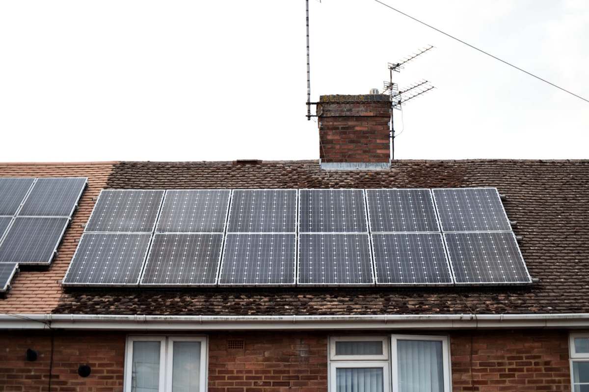 Solar panels installed on a roof with a chimney and satellite dish.