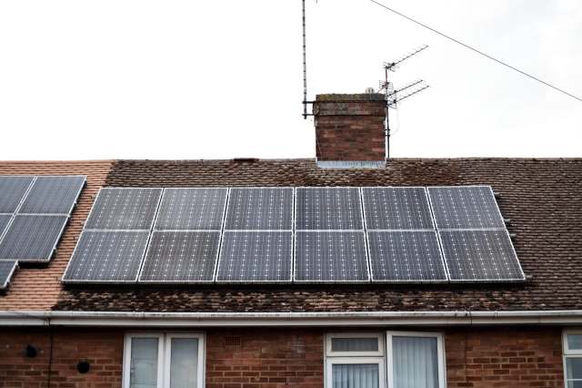 Solar panels installed on a roof with a chimney and satellite dish.