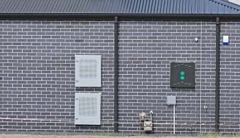 A gray brick wall with two utility boxes and a gas meter attached.