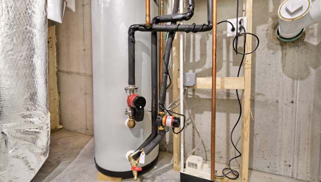 A water heater with connected pipes and valves in a basement setting.