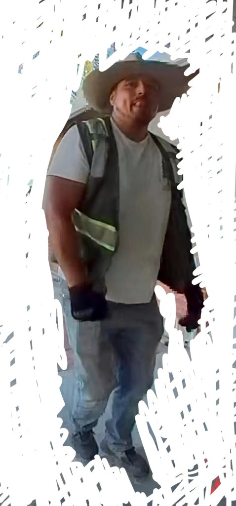 A man in a hat and a work vest and gloves.
