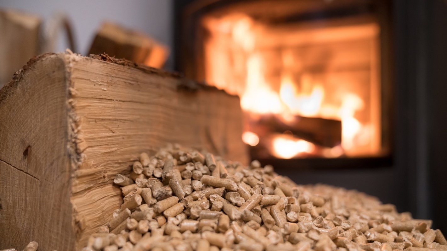 A pile of wood pellets in front of a glowing fireplace.