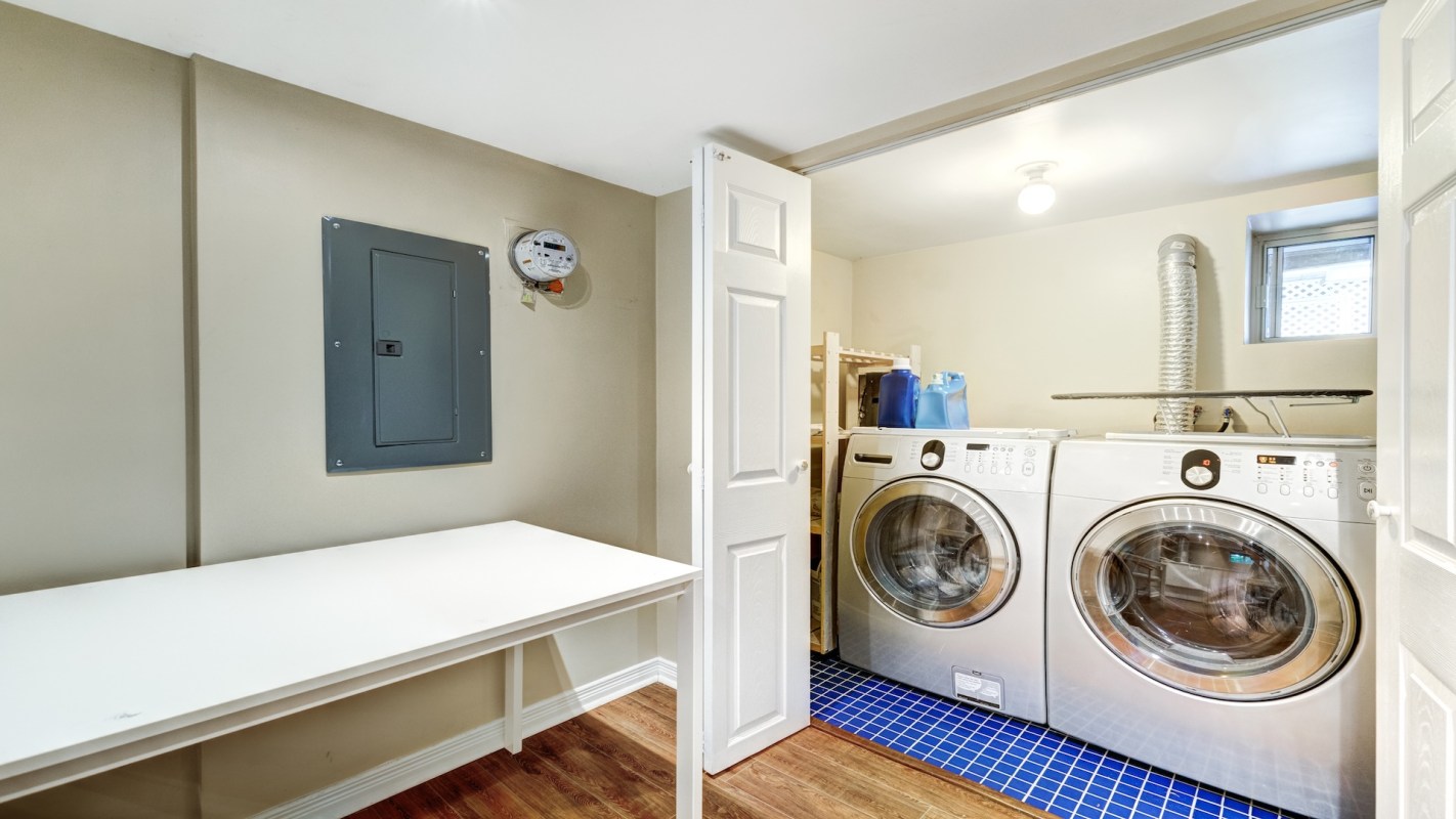 Laundry area featuring 2 machines, a table, and supplies