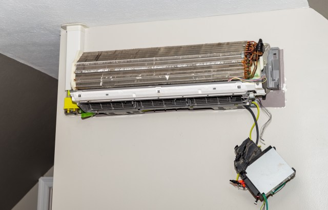 A mini-split air conditioning unit mounted on a wall with visible internal components and wiring.