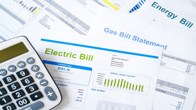 A calculator next to utility bills including an electric bill and a gas bill.