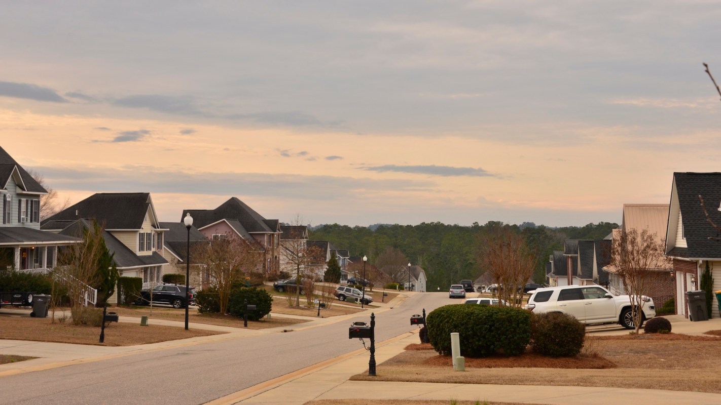 A residential street lined with houses and mailboxes under a cloudy sky.