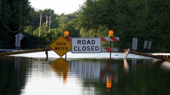 A flooded road with a "Road Closed" sign and "High Water" warning.