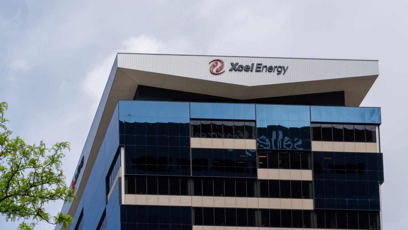 A modern building with large glass windows and a sign for Xcel Energy on the roof.