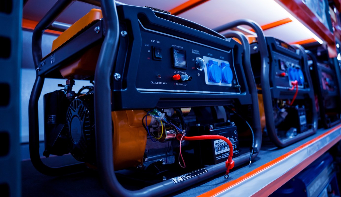Several portable generators with control panels are lined up on a shelf.