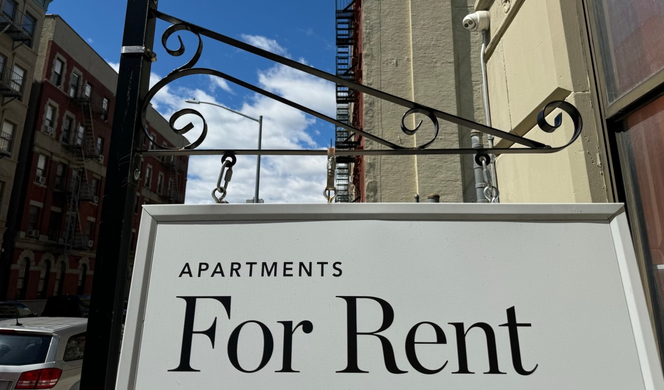 An "Apartment For Rent" sign hangs from an ornate New York City building,