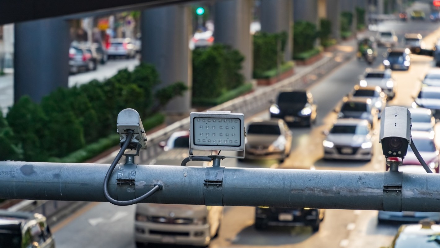 Traffic monitoring equipment overlooking a busy street with vehicles and greenery.
