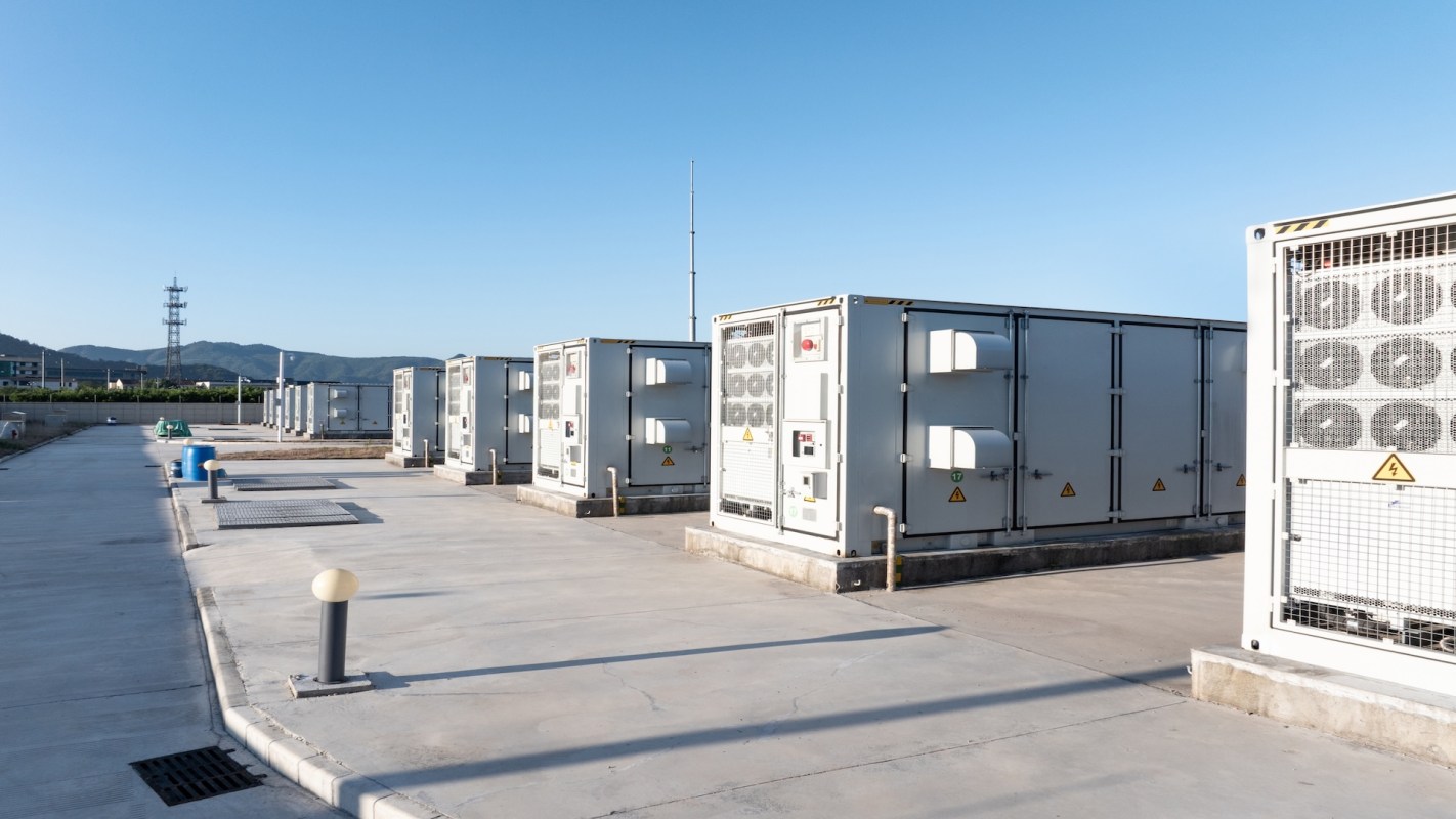 Several industrial cooling units arranged on a concrete surface with a clear blue sky above.