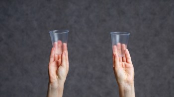 Hands holding empty plastic cups.