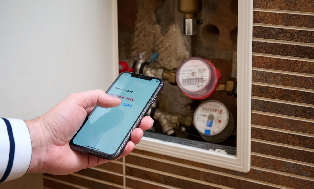 A person using a smartphone to track water meter readings.