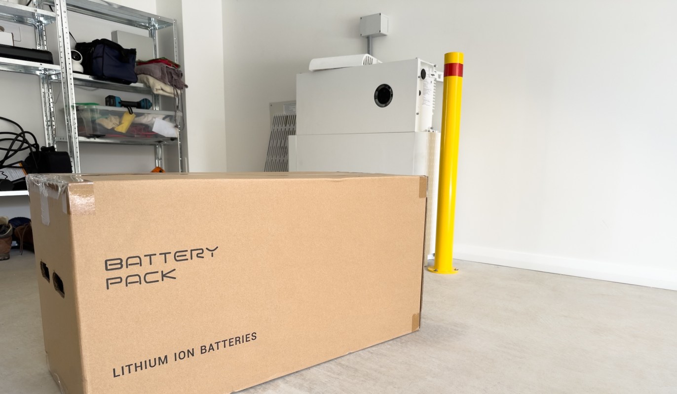 A box labeled "Battery Pack" for lithium ion batteries in a garage setting.