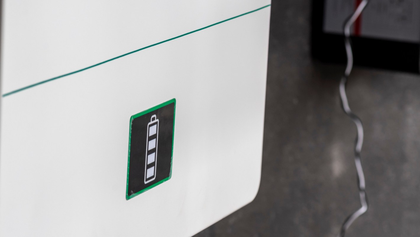A battery status indicator displayed on a white home battery with a cable connected.