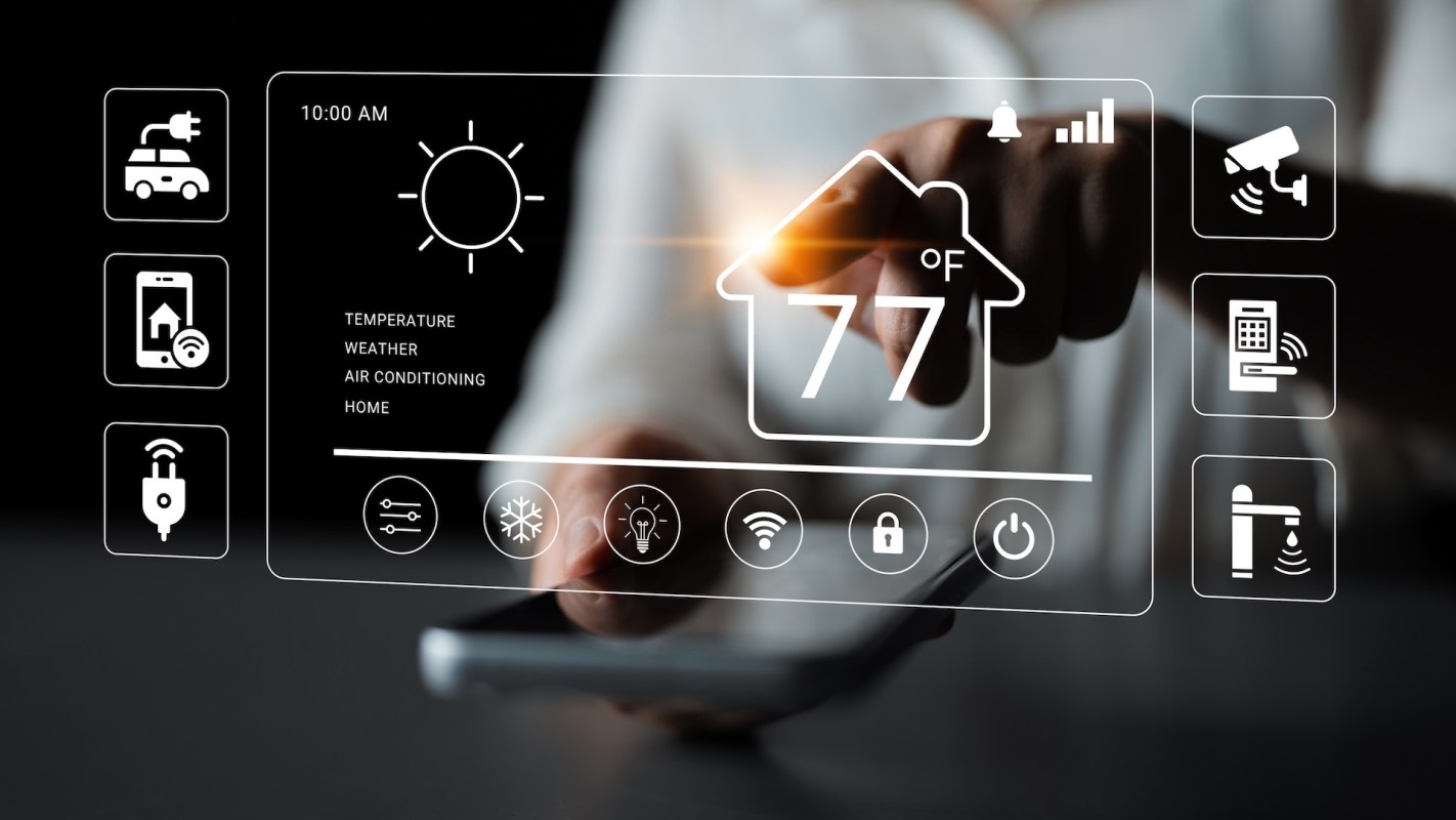 A hand interacts with a digital smart home control panel displaying temperature and various home settings.