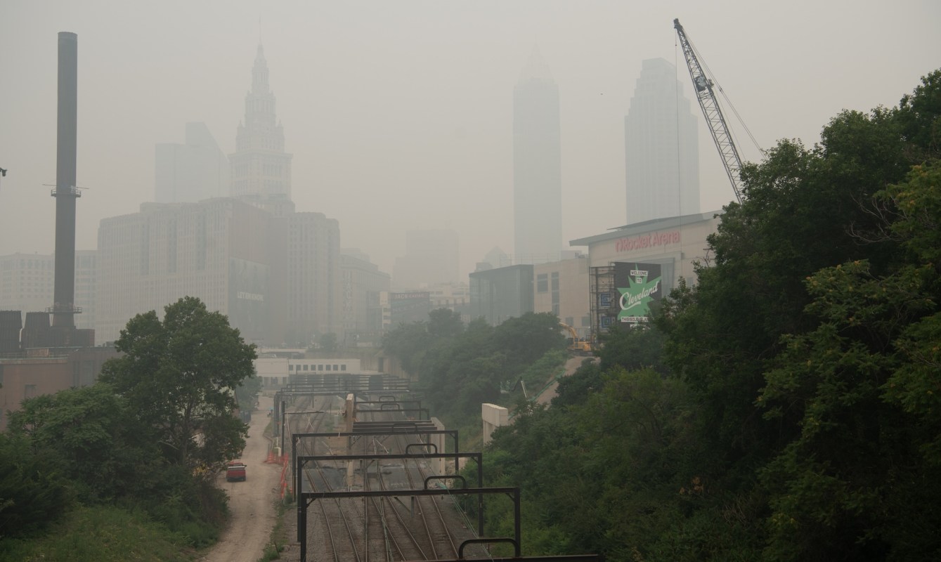A cityscape shrouded in haze, featuring skyscrapers and railway tracks in the foreground.