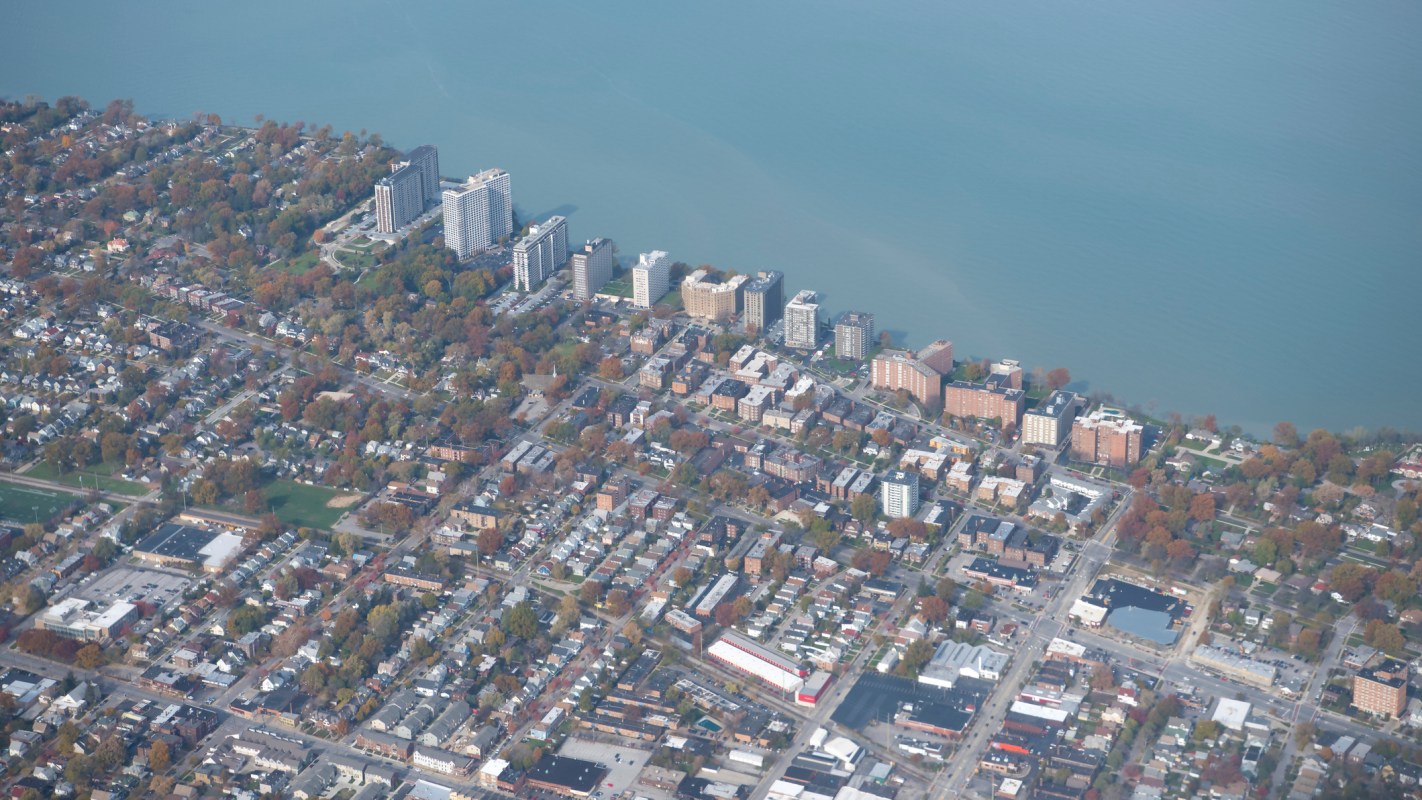 An aerial view of a city with residential buildings and a lake in the background.