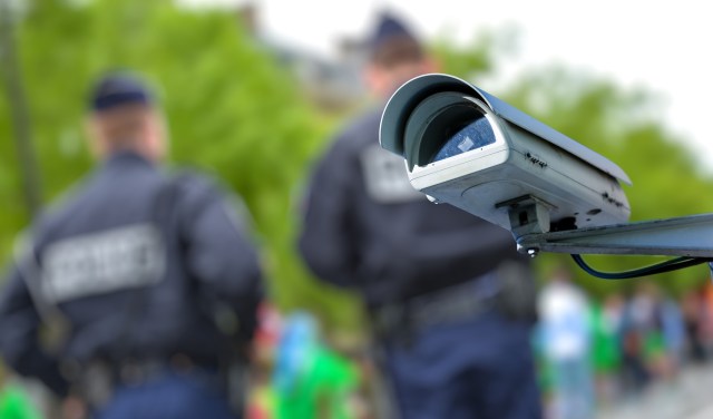 A security camera with blurred police officers in the background.