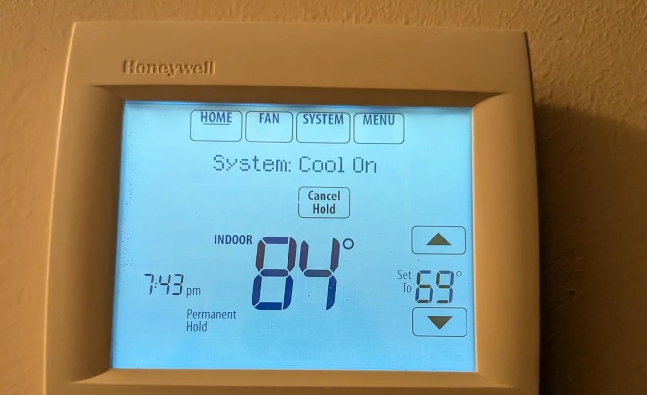A digital thermostat displaying an indoor temperature of 84°F.