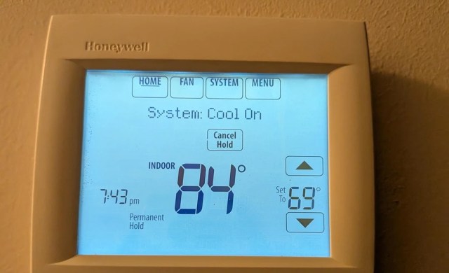 A digital thermostat displaying an indoor temperature of 84°F.