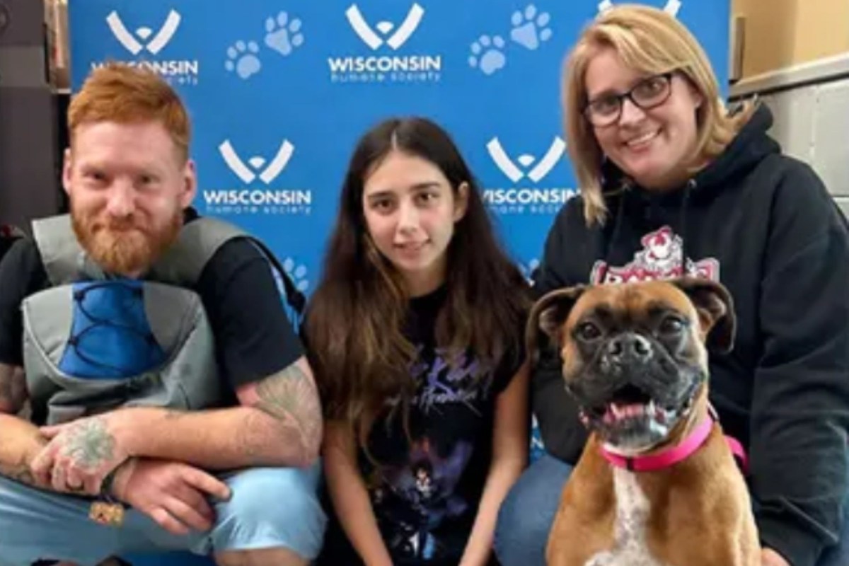 A family poses with a dog in front of a "Wisconsin Humane Society" backdrop.