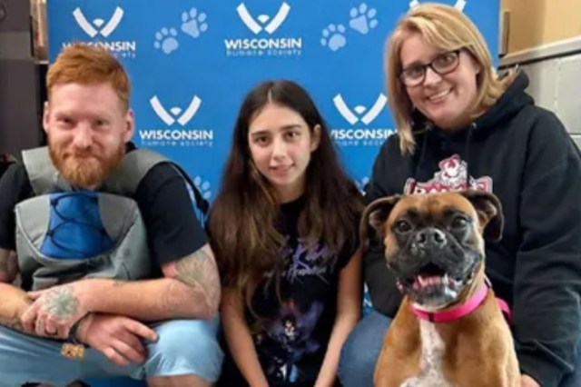 A family poses with a dog in front of a "Wisconsin Humane Society" backdrop.