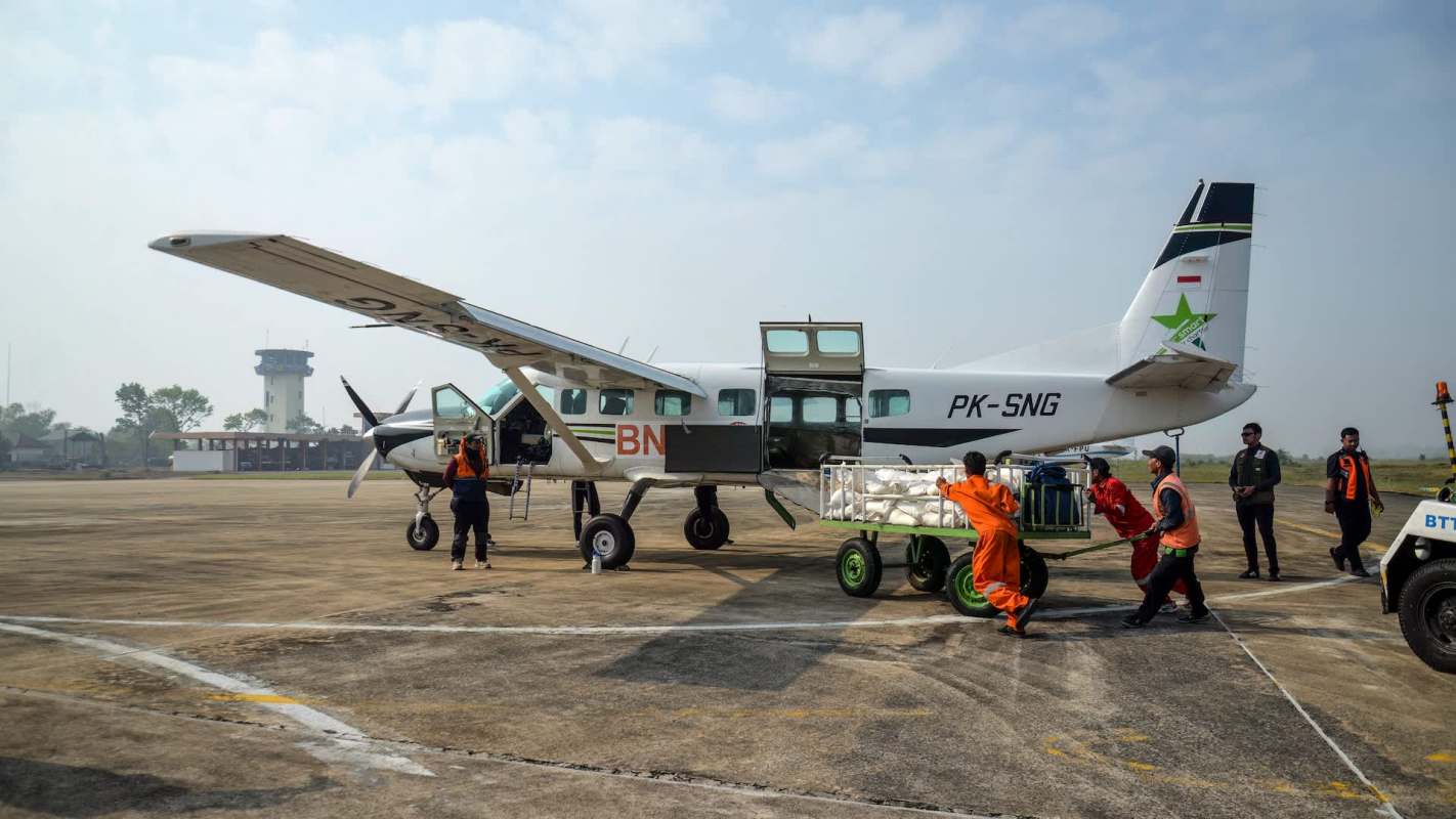 A team loading a plane with cloud-seeding supplies.