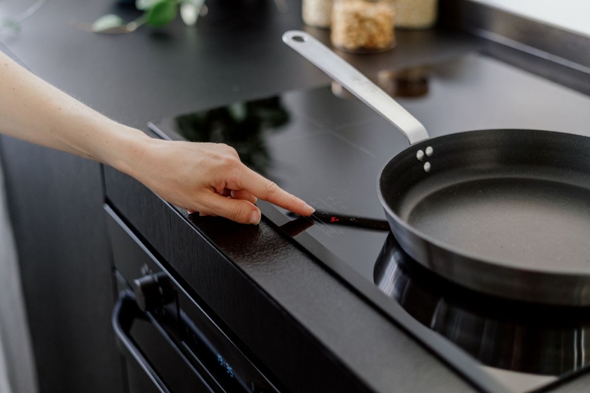 A person turning on an induction stove.
