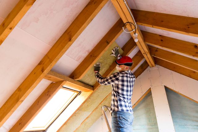 A man adding insulation to an attic.