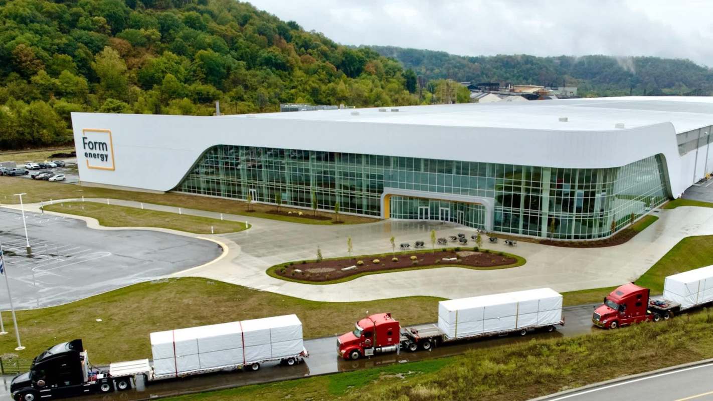 A modern building labeled "Form energy" with trucks parked outside in a landscaped area.