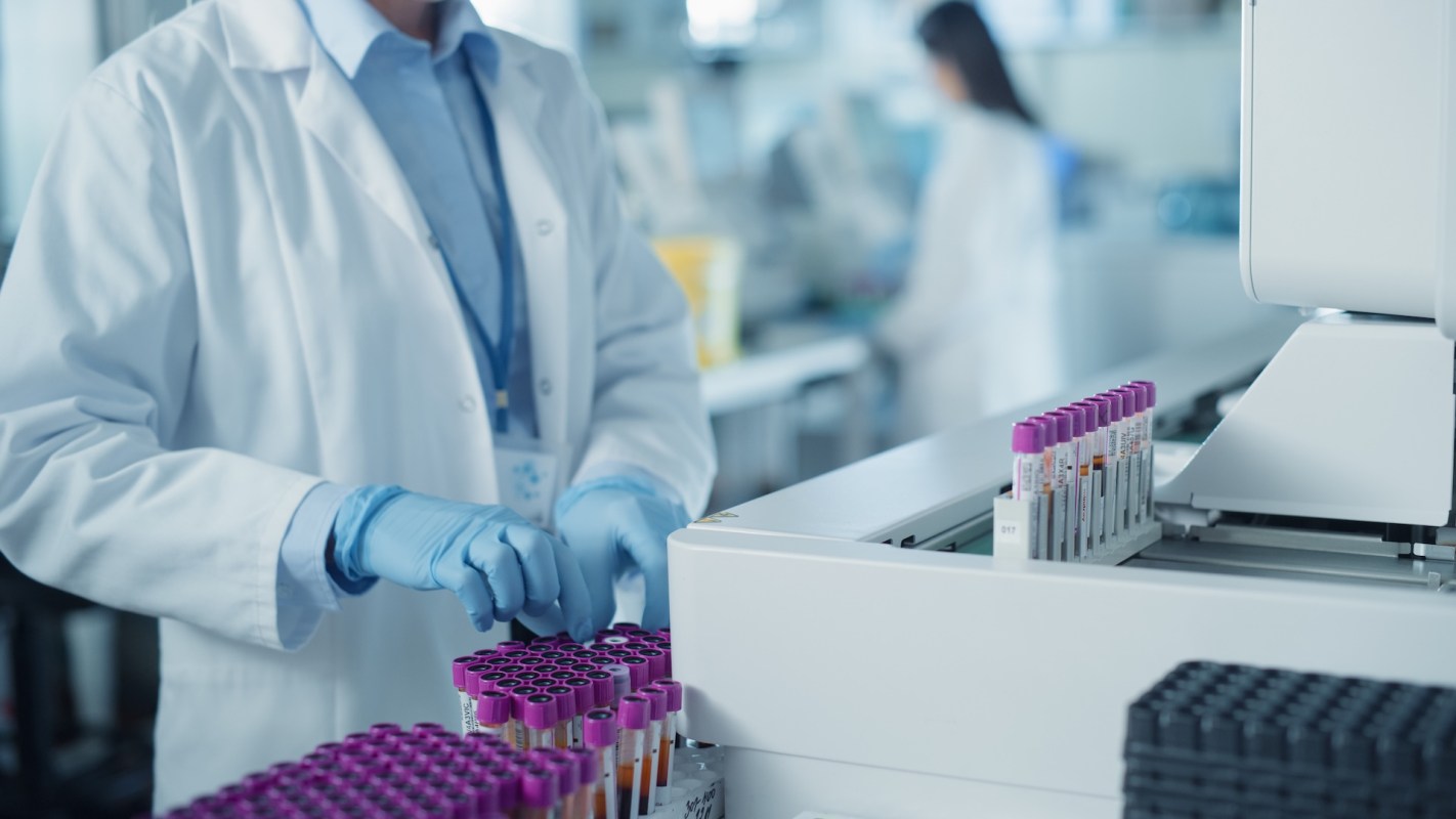 A lab technician handles test tubes in a laboratory setting.