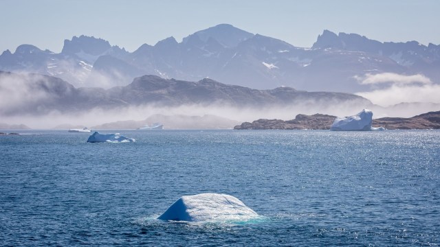 An Arctic landscape with icebergs and mountains.