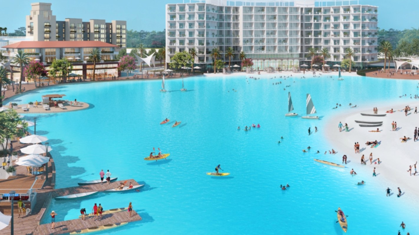 A luxury resort features a large blue lagoon with people kayaking, sailing, and enjoying the waterfront.
