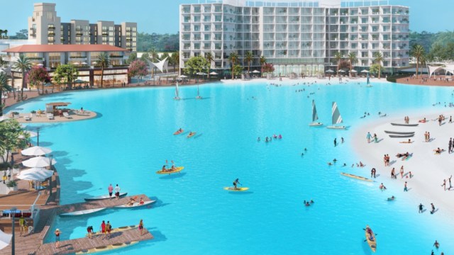 A luxury resort features a large blue lagoon with people kayaking, sailing, and enjoying the waterfront.