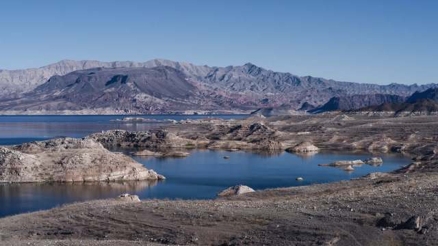 A panoramic view of a landscape with rocky formations and a low body of water surrounded by mountains.