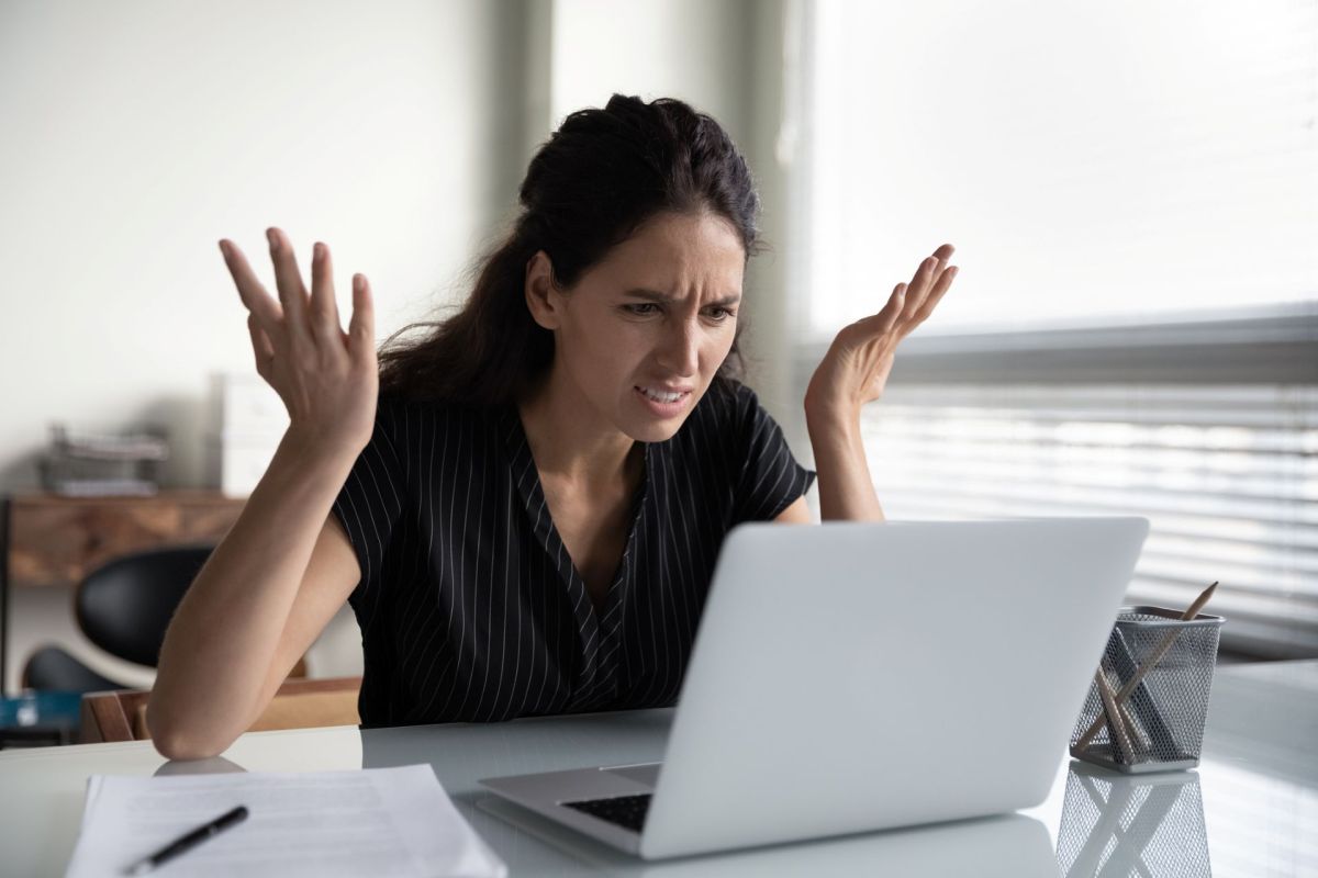 A frustrated person using a laptop.