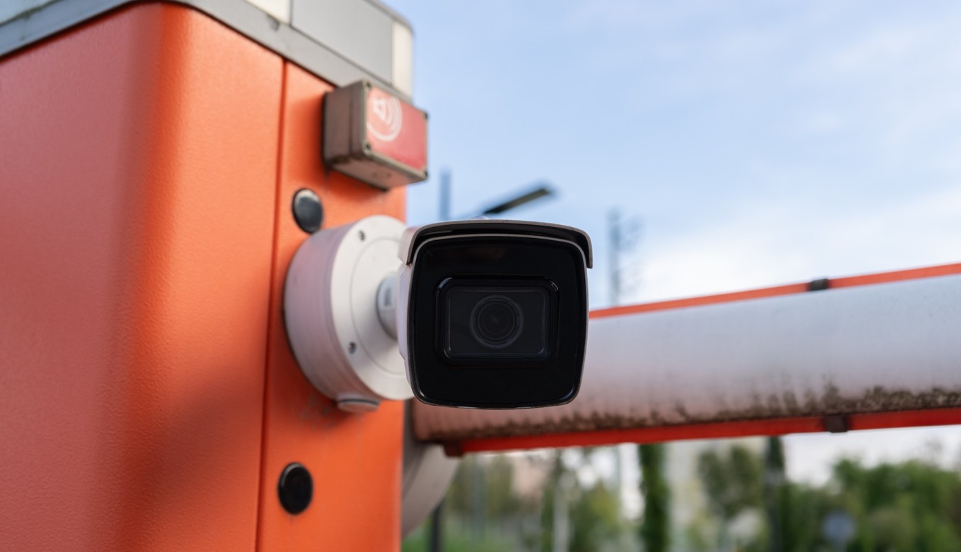A security camera mounted on an orange barrier.