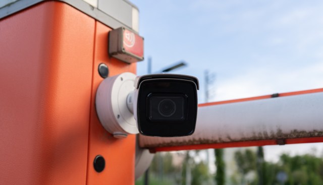 A security camera mounted on an orange barrier.