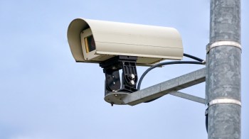 A surveillance camera on a metal pole.