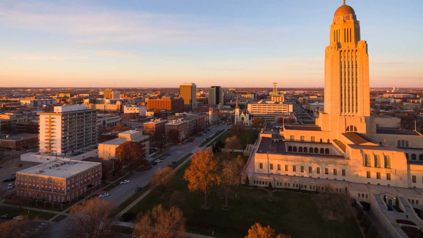 A panoramic view of a city skyline at sunset, featuring notable buildings and a prominent tower.