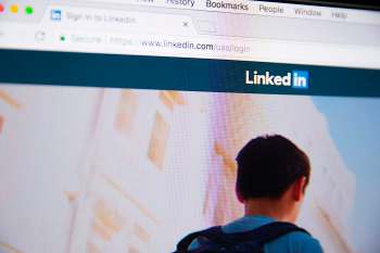 A computer screen displaying the LinkedIn login page with a user in the background.