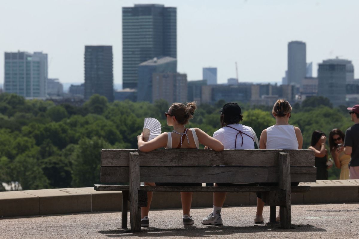 People sitting on a bench in London.